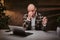 Bald european well-dressed tired businessman sitting in the office at a table with notebook, wearing stylish jacket