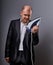 Bald fun unhappy menacing aggressive business man holding the home iron and wanting to hit in suit on grey background. Closeup