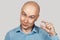 A bald guy shows a hand gesture meaning a very small amount of something