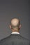 Bald headed businessman with barcode on his neck over gray background