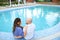 Bald husband and wife sitting barefoot near swiming pool.