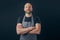 Bald male butcher or fishmonger in black t shirt and classic black and white apron on dark background. Meat industry. Hands