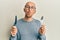 Bald man with beard holding fork and knife ready to eat looking at the camera blowing a kiss being lovely and sexy