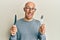 Bald man with beard holding fork and knife ready to eat smiling and laughing hard out loud because funny crazy joke