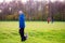 Bald man in blue hoodie with his pet Yorkshire terrier in a park on a green meadow in focus. Other people with dogs out of focus.