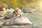 A bald man builds a tower of stones in the nature, against the b