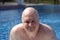 Bald Man in the fifties smiling in the pool-Stock photos