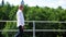 A bald man going along on an abandoned railway bridge and sings. Medium shot.