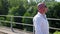 A bald man going along on an abandoned railway bridge and sings. Medium shot.