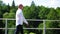 A bald man going along on an abandoned railway bridge and sings. Medium shot.