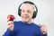 Bald man with headphones listens to music through a red apple player. Metaphor and concept of vitamin benefits in music and sound