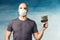 A bald man in a mask wearing a respirator holds a spatula and prepares for repair on a blue background.