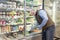 A bald man in a medical mask and gloves chooses frozen foods in a supermarket refrigerator. Proper nutrition and a healthy