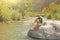 A bald man sits on a large rock against a background of a mountain river, on a nature. Man is a traveler. Gorge of Alcantara, Sic