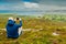 Bald man taking picture on his smart phone of scenic view on Clew Bay from Croagh Patrick,