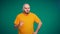 Bald middle-aged man with a beard in an orange t-shirt chews and wrinkles. The man doesn\'t like the food.