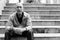 Bald senior man leaning arms on knees while sitting on the staircase in Bangkok Thailand