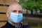 Bald senior man in medical protective face mask looks at the camera