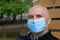 Bald senior man in medical protective face mask looks at the camera