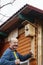 Bald senior with a mustache attaches birdhouse to the barn