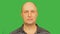 Bald serious man looking at camera and trying to smile. Alpha channel, keyed green screen.