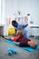 Bald sportsman lying on mat and having physical therapy for legs