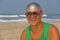 A bald and unusual young man, a freak, with a shiny bald head and round wooden glasses on the background of the beach and the sea