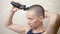 Bald woman shaves her head with an electric razor. close-up, copy space