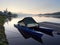 Baldeneysee lake just before sunrise. A small, moored boat on the lake covered with a cover. A boat with two hulls