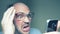 A balding man with glasses uses a smartphone. gesture surprise victory. Humor