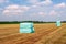 Bales of compressed hay packed with foil and stacked on mown grassland