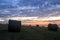 Bales of harvested wheat on the cliff edge during sunset