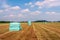 Bales of hay packed with foil and stacked on mown grassland