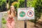 BALI, INDONESIA - 21 May, 2018: Young woman looks at protest sign on a wall in Indonesian objecting to Uber and Grab taxi drivers