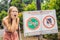 BALI, INDONESIA - 21 May, 2018: Young woman looks at protest sign on a wall in Indonesian objecting to Uber and Grab taxi drivers