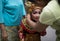 BALI/INDONESIA-DECEMBER 28 2018: a Balinese dancer, a small woman, is putting on a headdress helped by her mother. A soothing