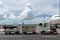 BALI/INDONESIA-MARCH 27 2019: Airport vehicles pulls passengers baggage to the arrival terminal when the sunny day with cumulus