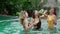 BALI, INDONESIA - NOVEMBER 8, 2017: Girlfriends in the pool. Party in the summer holidays. Girls clink glasses with