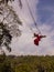 Bali swing trend. Caucasian woman in long red dress swinging in the jungle rainforest. Vacation in Asia. Travel lifestyle. Blue