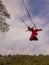 Bali swing trend. Caucasian woman in long red dress swinging in the jungle rainforest. Vacation in Asia. Travel lifestyle. Blue