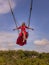 Bali swing trend. Caucasian woman in long red dress swinging in the jungle rainforest. Vacation in Asia. Travel lifestyle. Blue