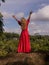 Bali trend photo. Caucasian woman in long red dress standing on big stone in tropical rainforest. Vacation in Asia. Travel