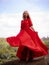 Bali trend photo. Caucasian woman in long red dress standing on big stone in tropical rainforest. Vacation in Asia. Travel