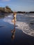 Bali yoga. Slim woman practicing Vrikshasana, Tree Pose on the beach. Hands raised up in namaste mudra. Water reflection. Balance