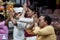 A Balinese family is praying with flowers on their fingers at a temple in Ubud, Bali.