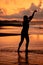 A Balinese woman in the form of a silhouette performs ballet movements very deftly and flexibly on the beach with the waves