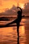 A Balinese woman in the form of a silhouette performs ballet movements very deftly and flexibly on the beach with the waves