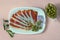 Balkan cuisine . White plate with slices of prsut dry-cured ham, prosciutto on pink pastel background, flat lay