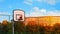 Ball in basketball hoop with blue sky at sunset