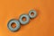 Ball bearings of different sizes on an orange background, top view.